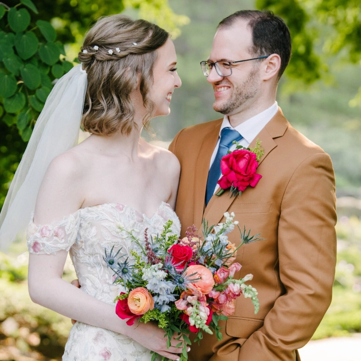 Samantha and Michael looking lovingly into eachothers eyes while sitting on a large chair in front of lake Mendota at the Memorial Union Terrace